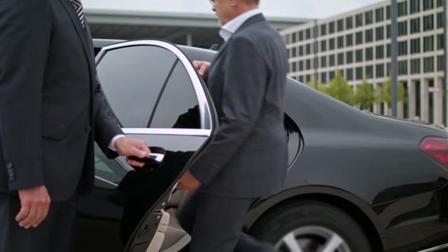 male passenger getting in the back of the car